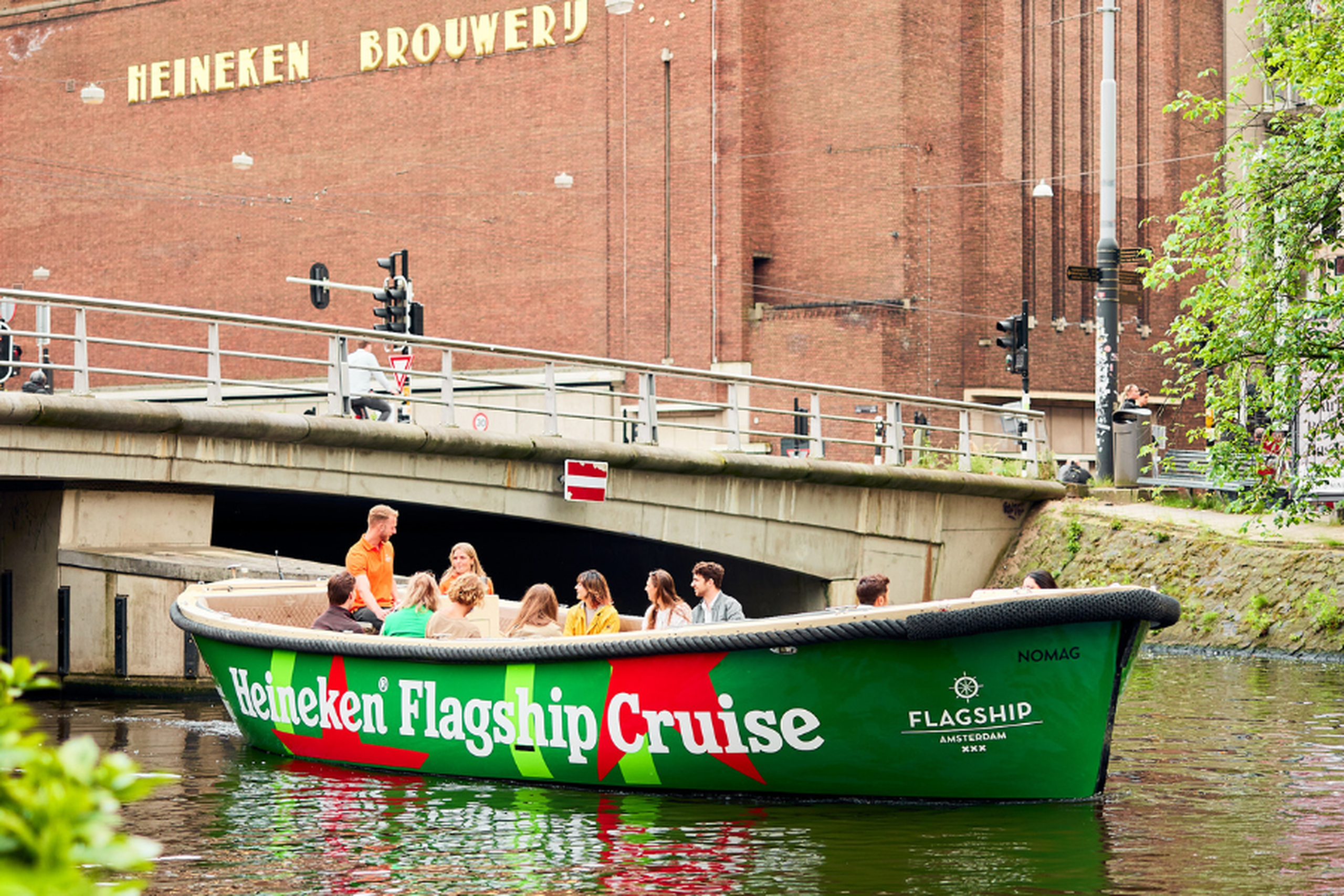 A group of people enjoying the Heineken Flagship Cruise on a scenic canal in Amsterdam.
