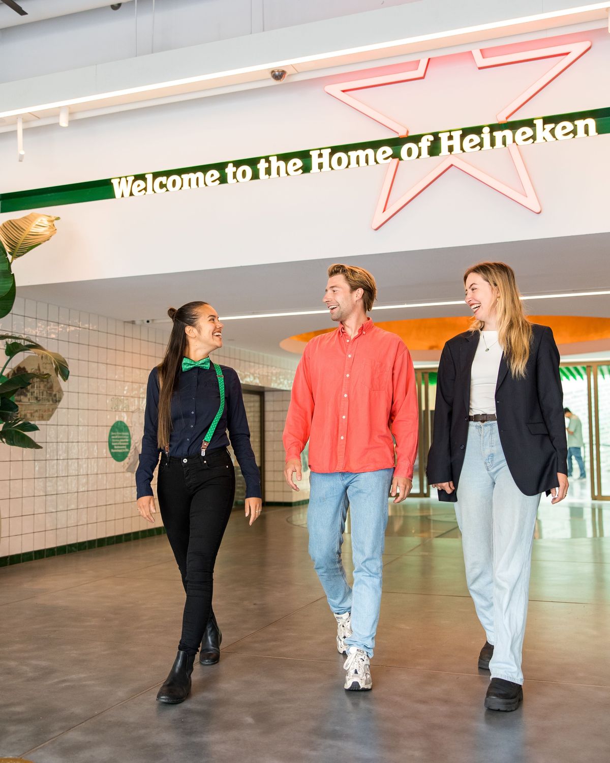 Three people walking together in the Heineken Experience entrance.
