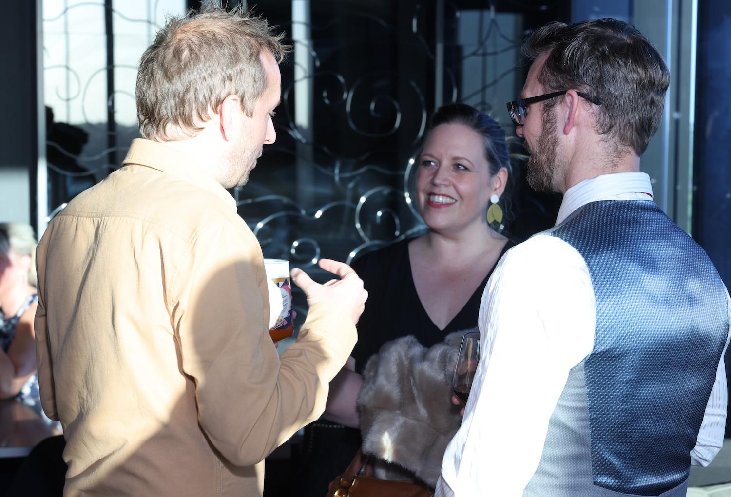 3 members of the Tennick Accountants team at their awards night. They're keep in discussion, and the person who is facing the camera is smiling.