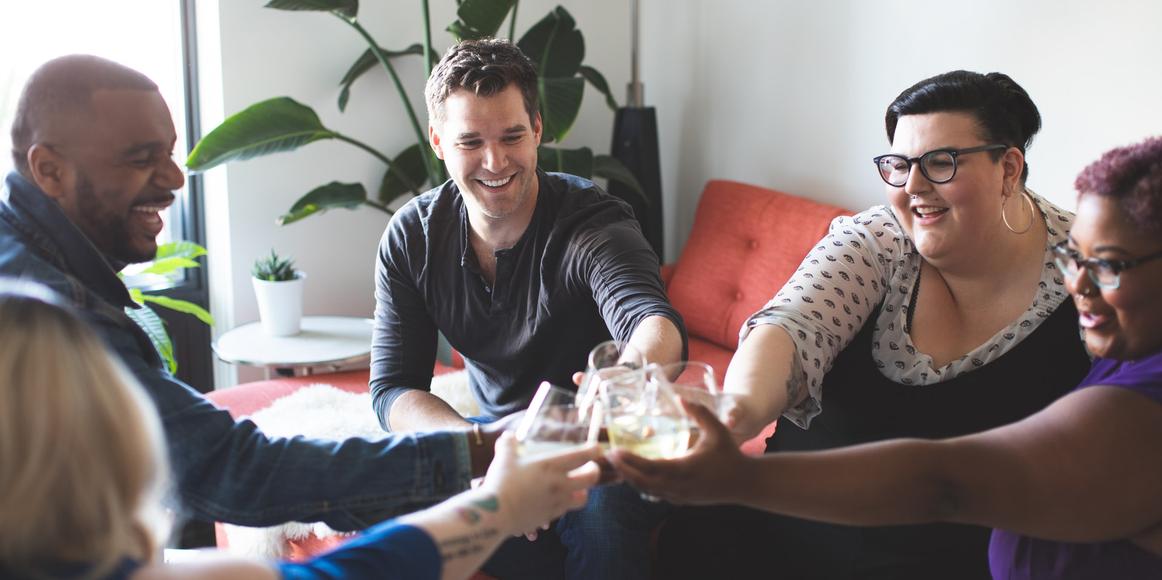 A group of people smiling and clinking their glasses.