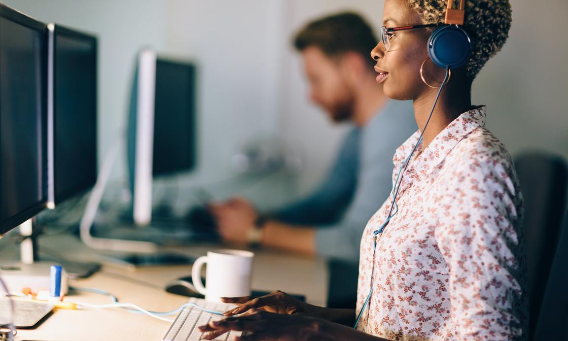 A person working at a desk, in front of a double-screen desktop computer.