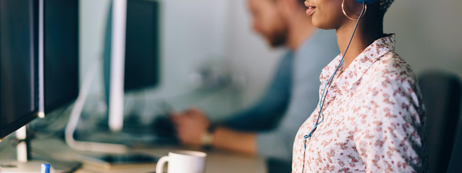 A person working at a desk, in front of a double-screen desktop computer.