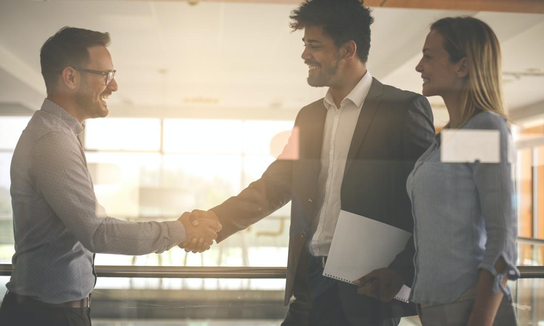 An accountant is smiling and shaking hands with a new lead that has been successfully converted into a client