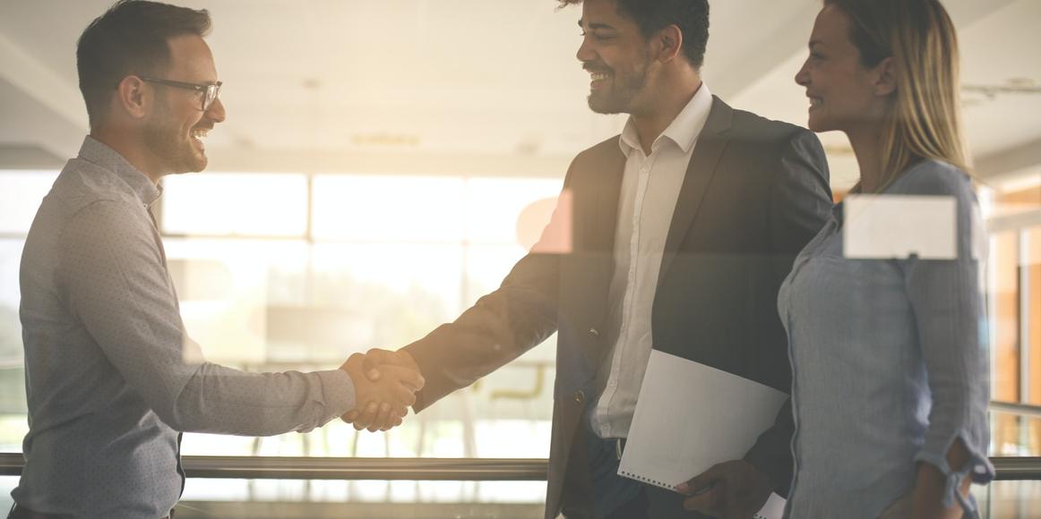 An accountant is smiling and shaking hands with a new lead that has been successfully converted into a client