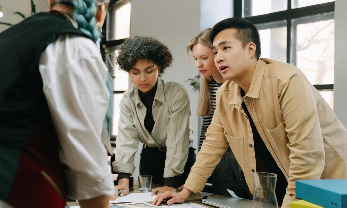 Four colleagues in an office engaged in a meeting, illustrating collaborative efforts in understanding private equity in accounting.