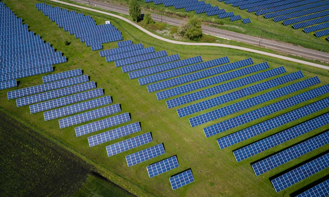 An arial view of a solar panel farm on top of a green field.