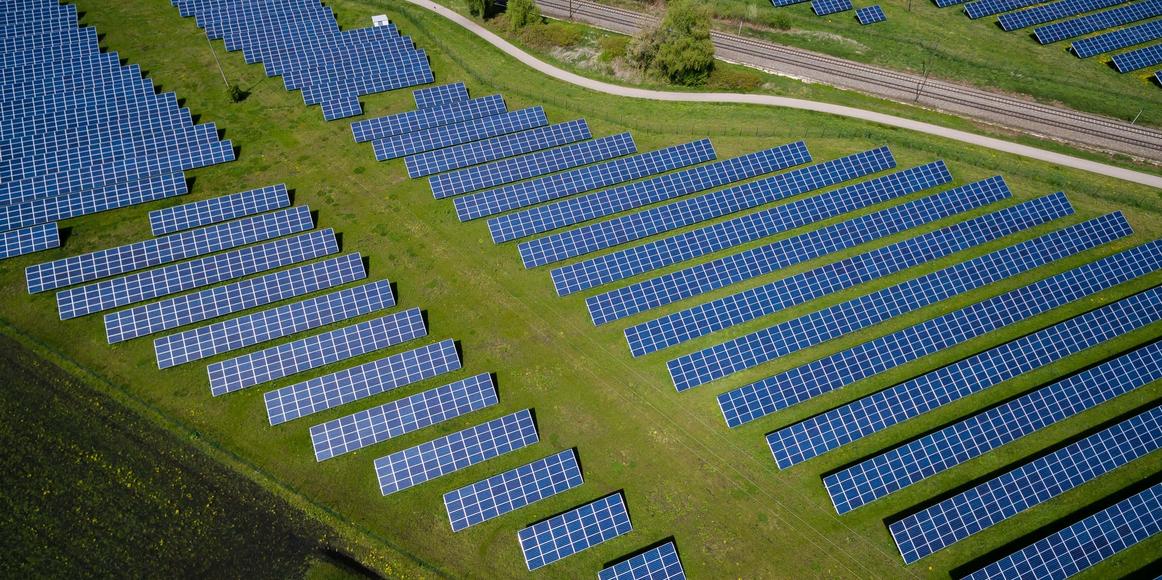 An arial view of a solar panel farm on top of a green field.