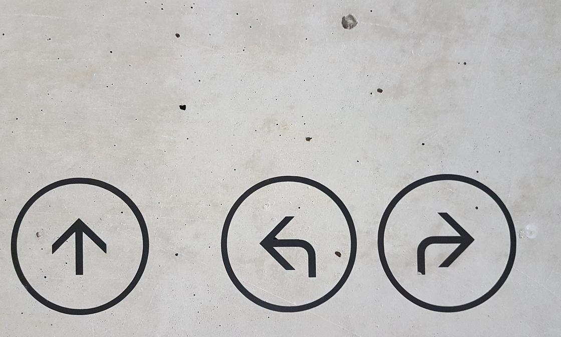 A gray concrete surface with 3 painted arrows, pointing up, left and right.