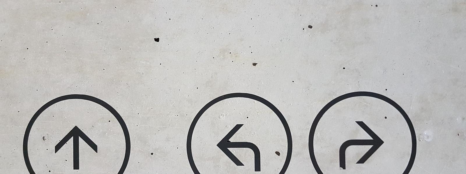 A gray concrete surface with 3 painted arrows, pointing up, left and right.