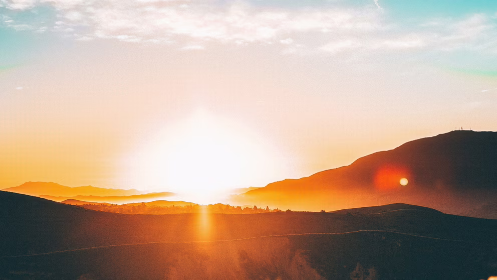 A sun rising over mountains
