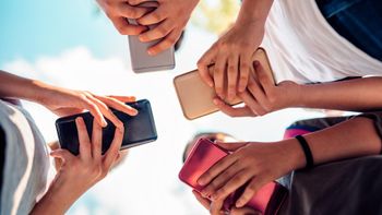 Four kids holding their phones, photo was taken from the bottom up so you see the back of the phones