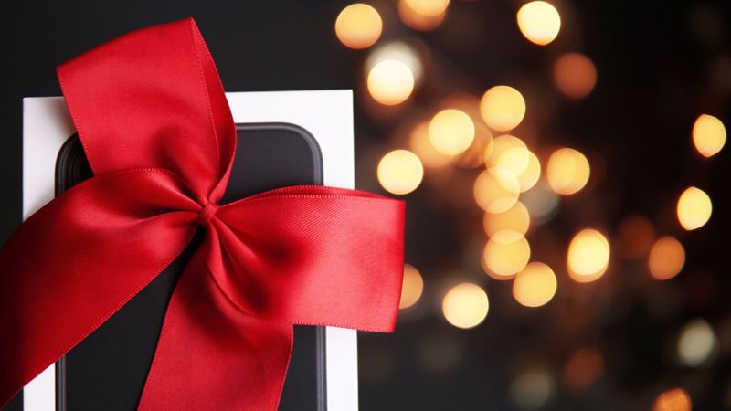 Smartphone wrapped with a red ribbon, yellow lights in the background