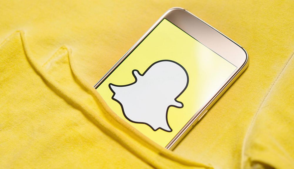 Yellow shirt with phone in chest pocket displaying the Snapchat logo