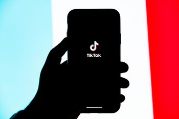 close-up of person opening tiktok on phone, brand colors in background