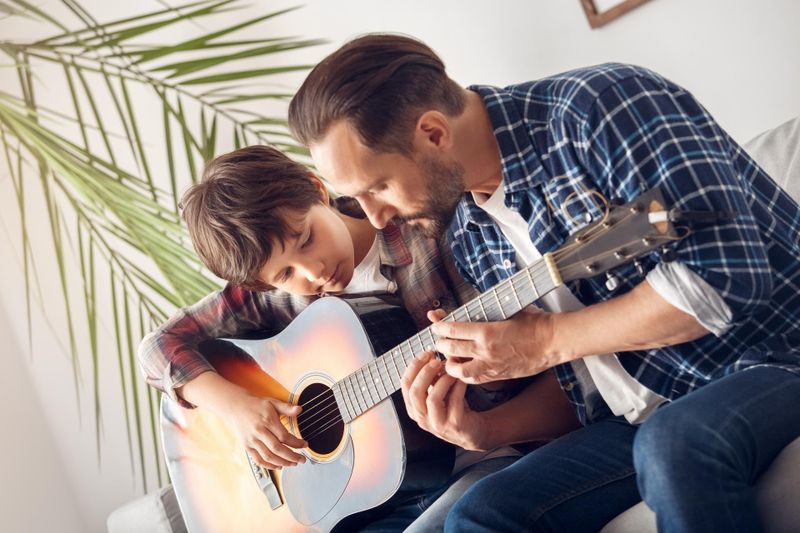Father teaches his son how to play the guitar