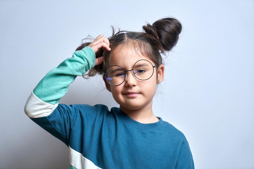 Little girl with glasses scratches her head