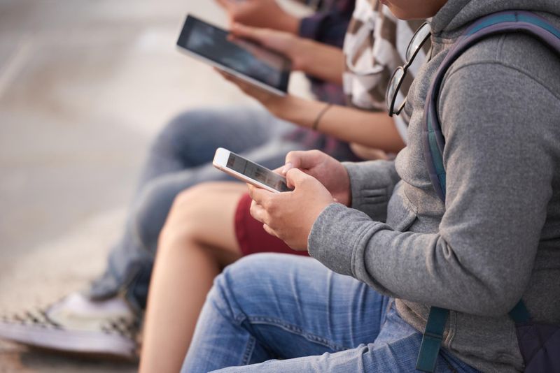 Kids looking at their smartphones and tablets next to each other