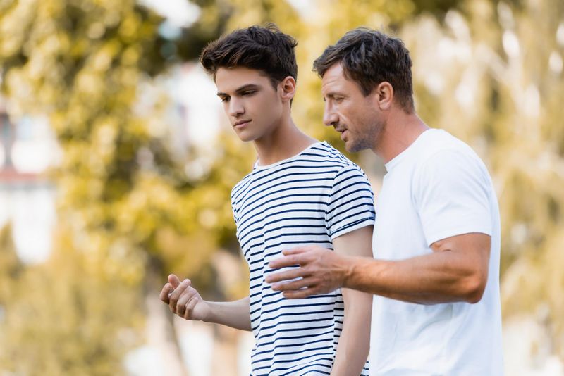 Father and teenage son are walking outside, having a conversation