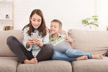 Ältere Schwester zeigt ihrem kleinen Bruder etwas Lustiges auf ihrem Smartphone