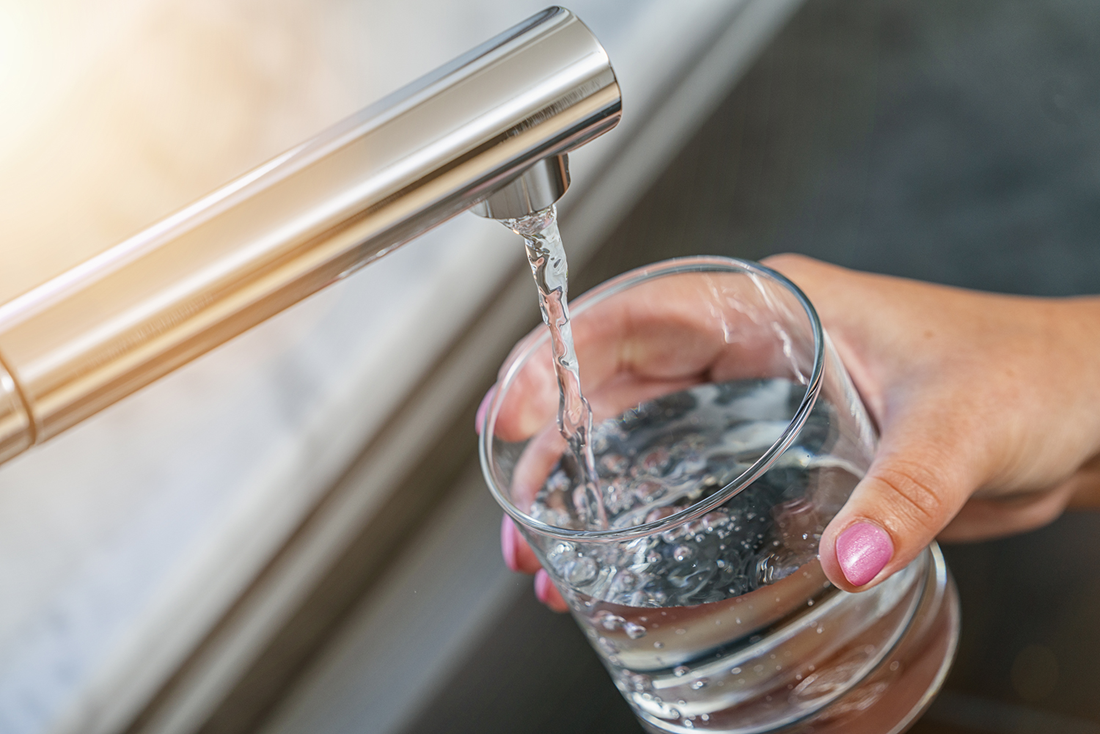 Person hält Wasser unter Wasserhahn