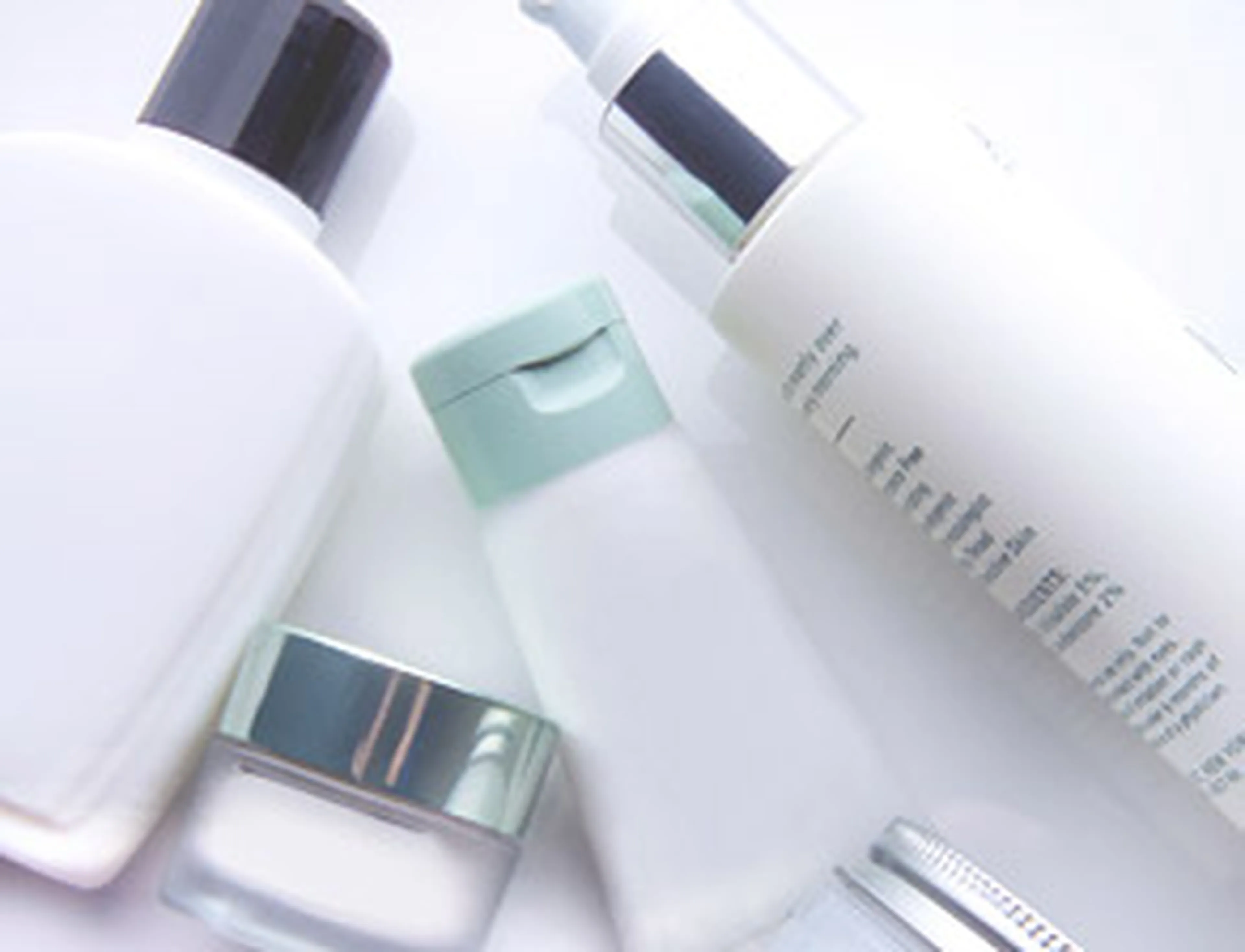 Various skincare containers, including bottles and jars, in white and pastel colors, arranged on a light background.