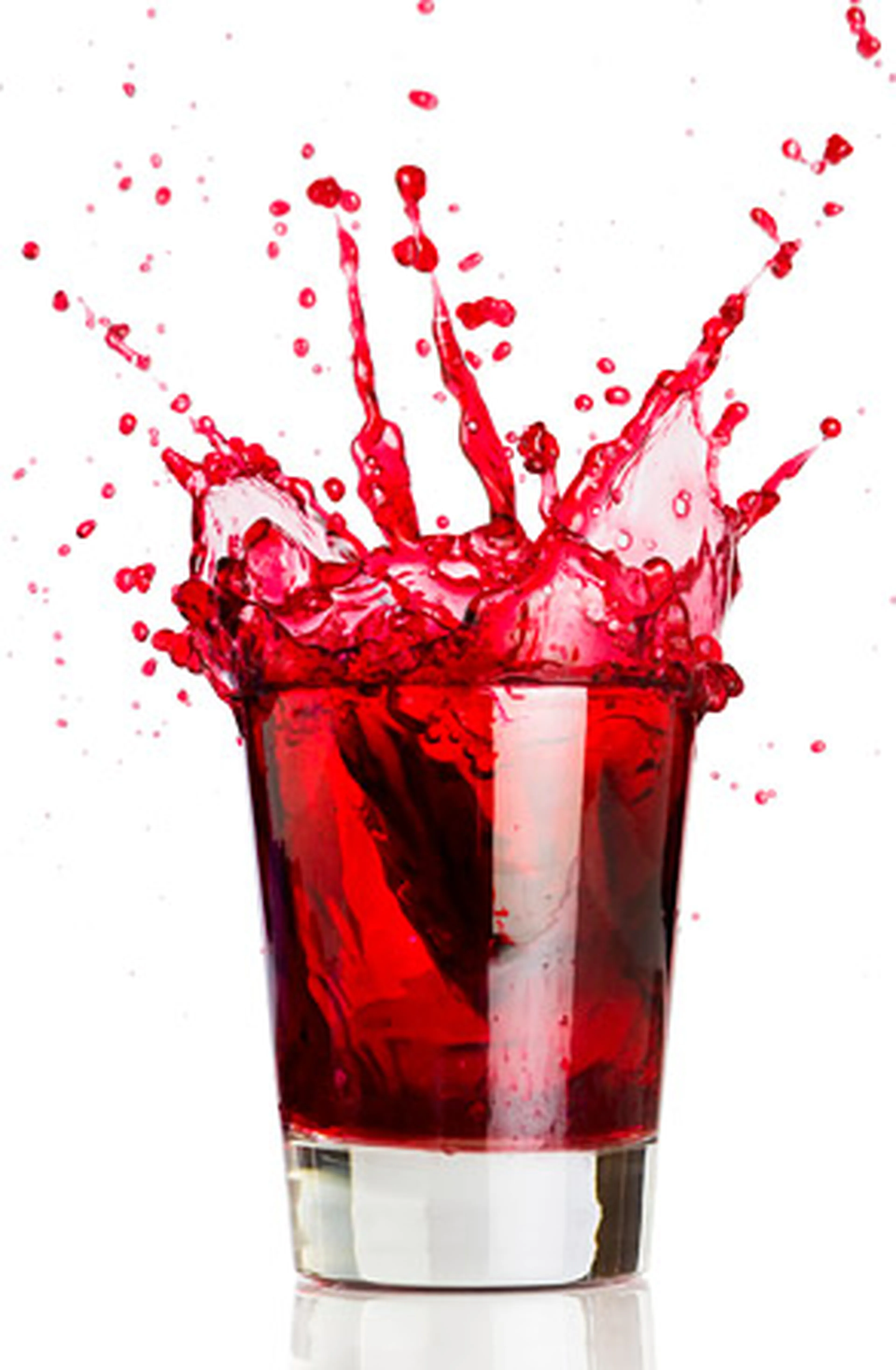 Red liquid splashing out of a clear glass against a white background, creating dynamic droplets and waves in the air.