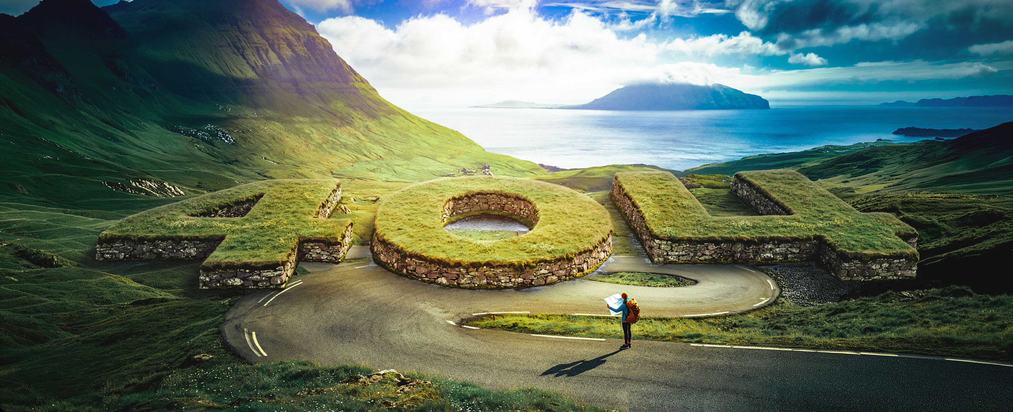 A person with a backpack and a map stands on a winding mountain road, overlooking lush green hills and a distant ocean view under a cloudy sky.