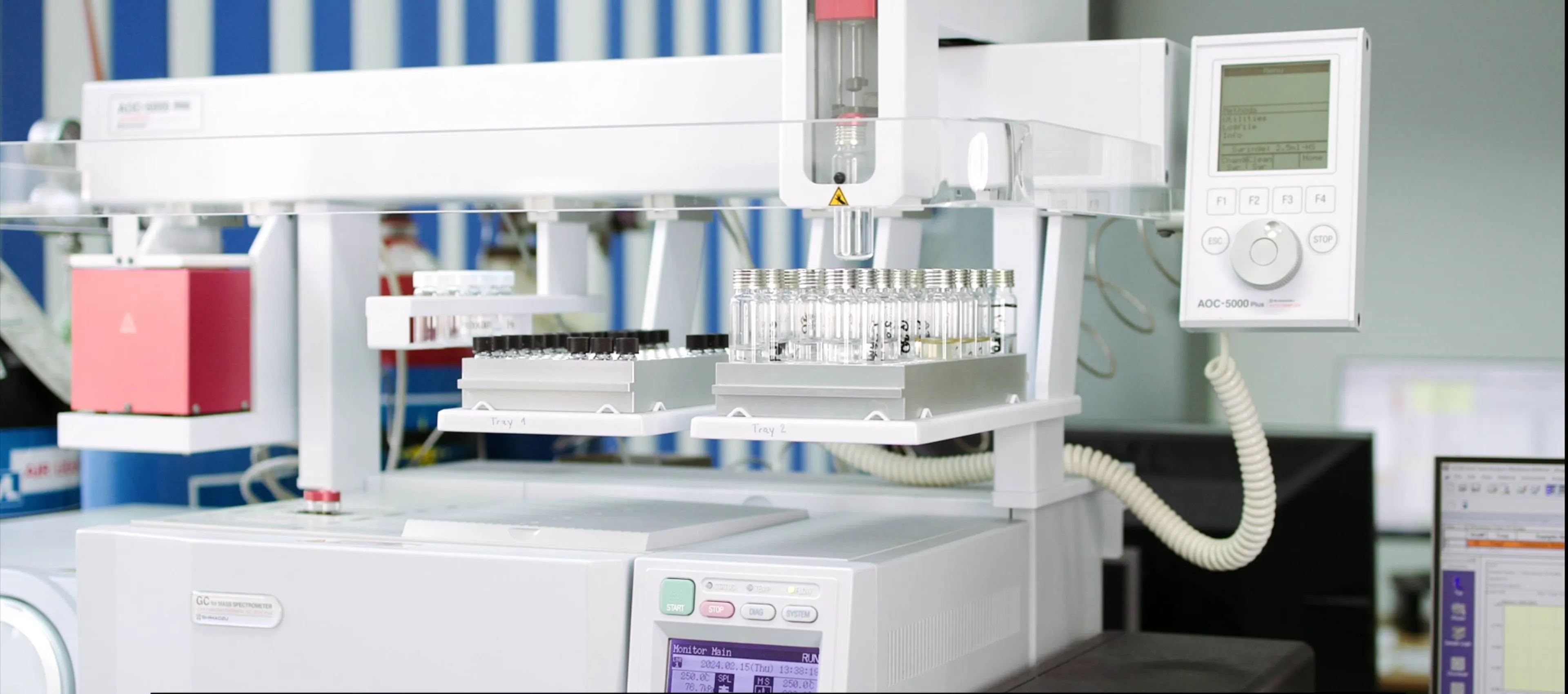 A laboratory machine with vials on trays and a digital control panel, used for automated processes.