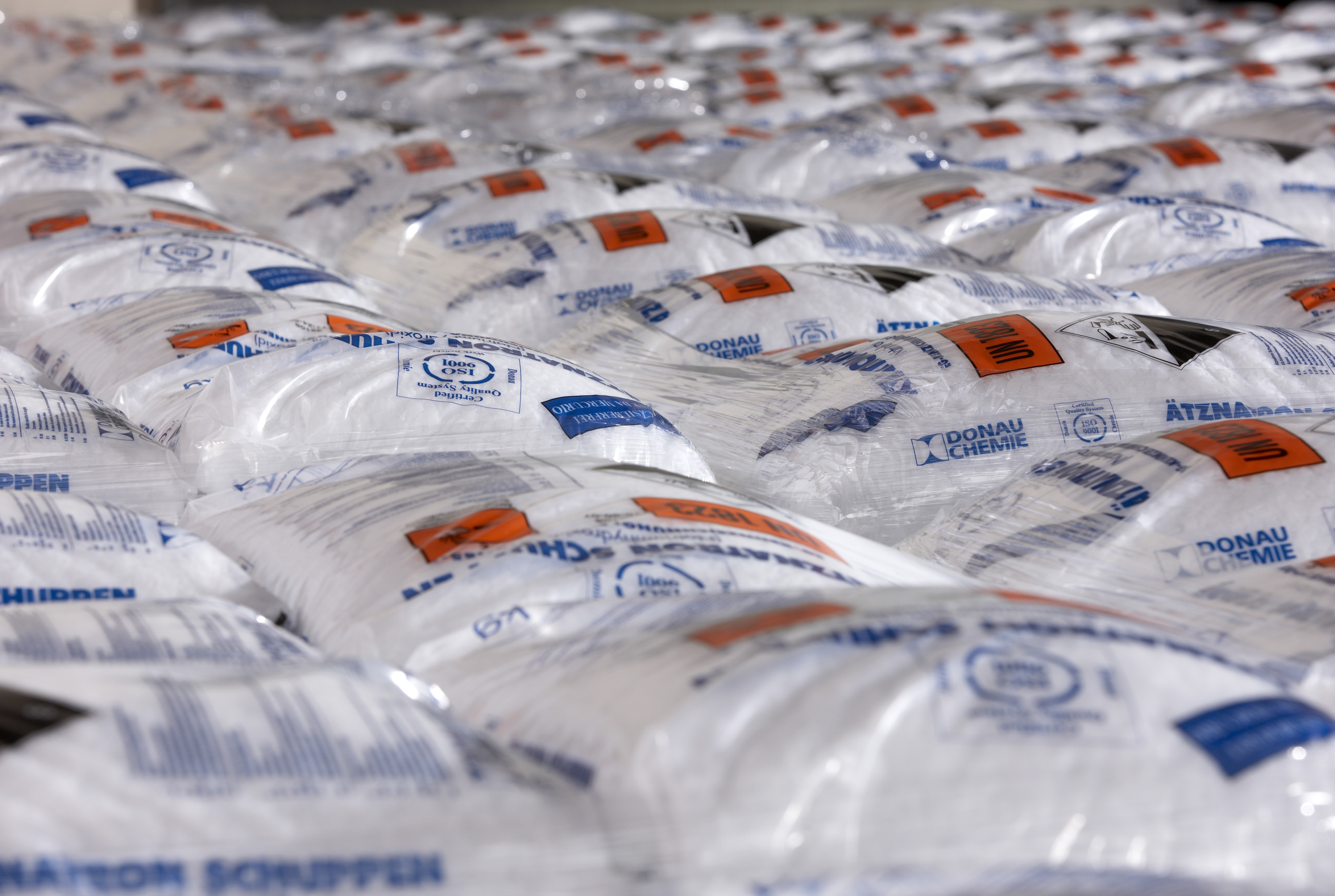 Rows of white bags with blue and orange labels, likely containing industrial materials, stacked closely together.