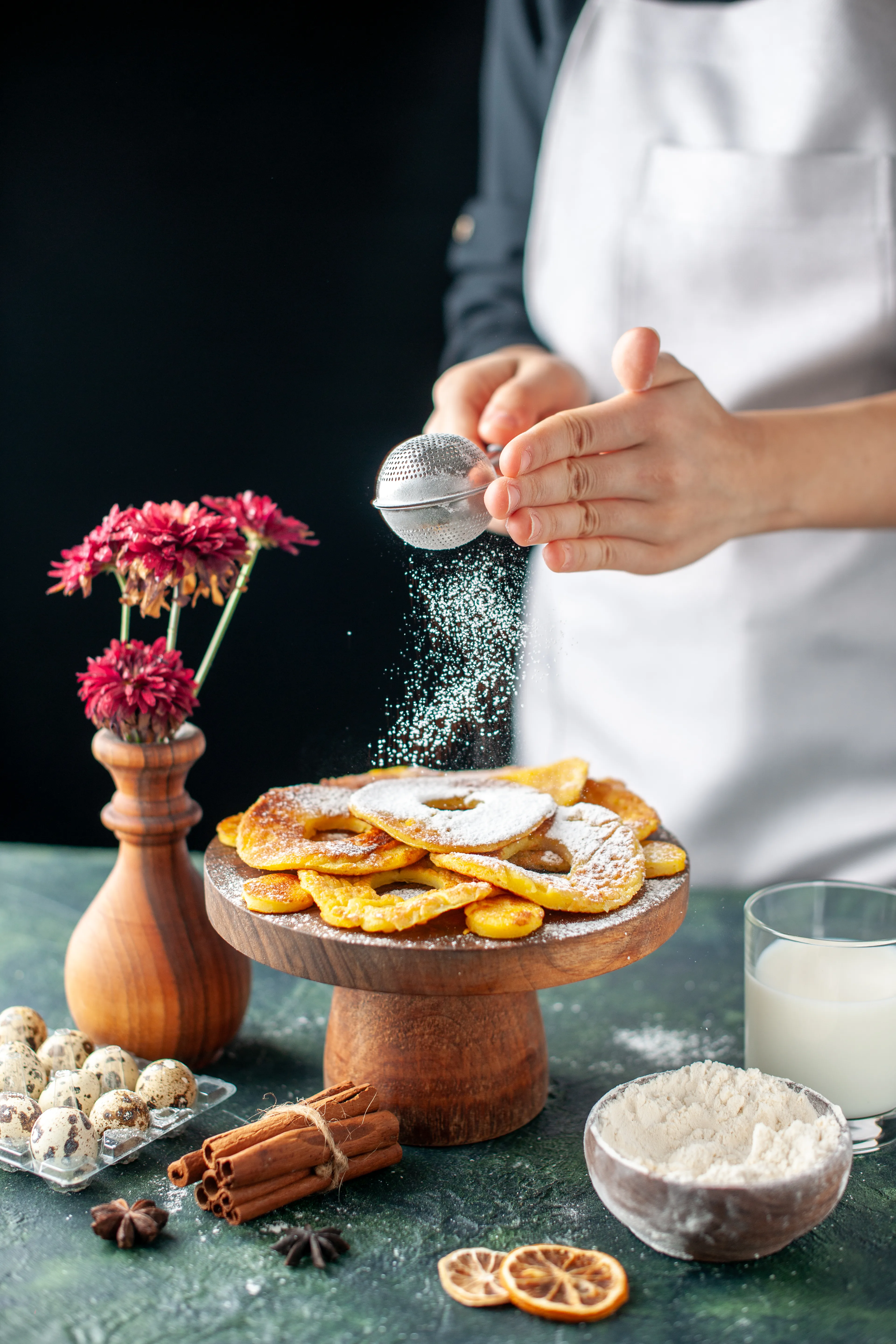 front-view-female-cook-pouring-sugar-powder-dried-pineapple-rings-dark-fruit-cooking-job-cake-pie-bakery