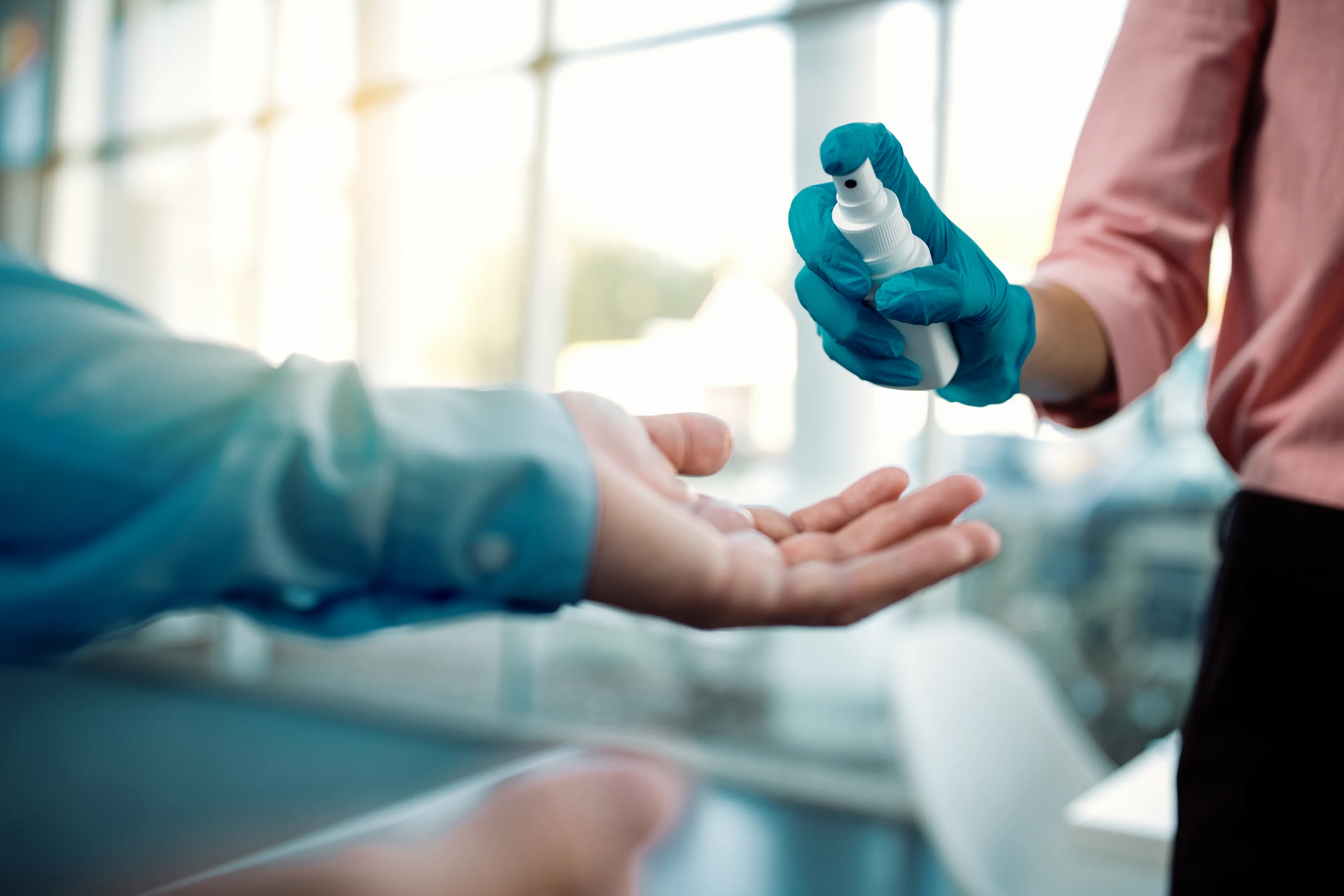 Person sprüht Desinfektionsmittel in Hand