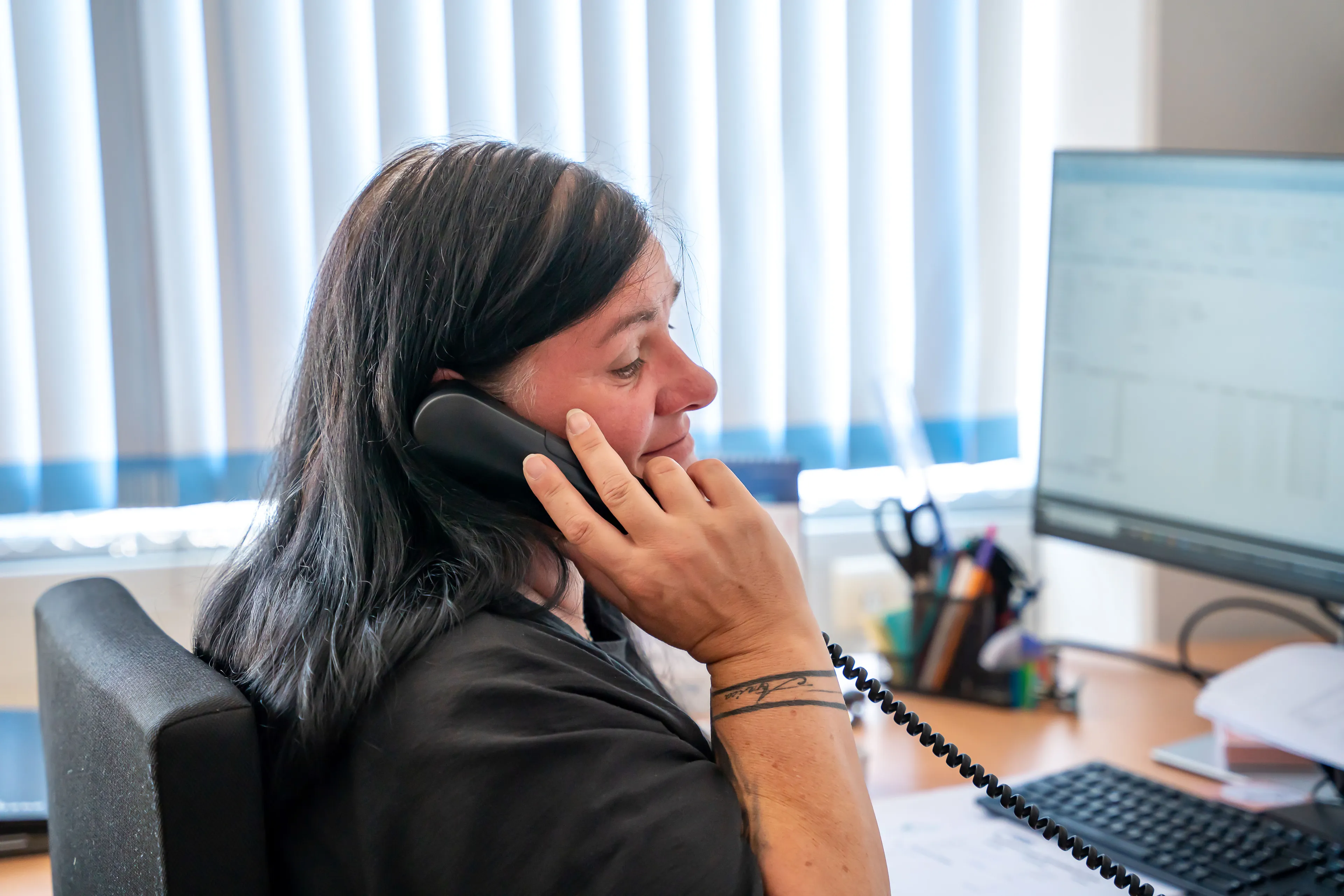 Frau telefoniert vor Schreibtisch