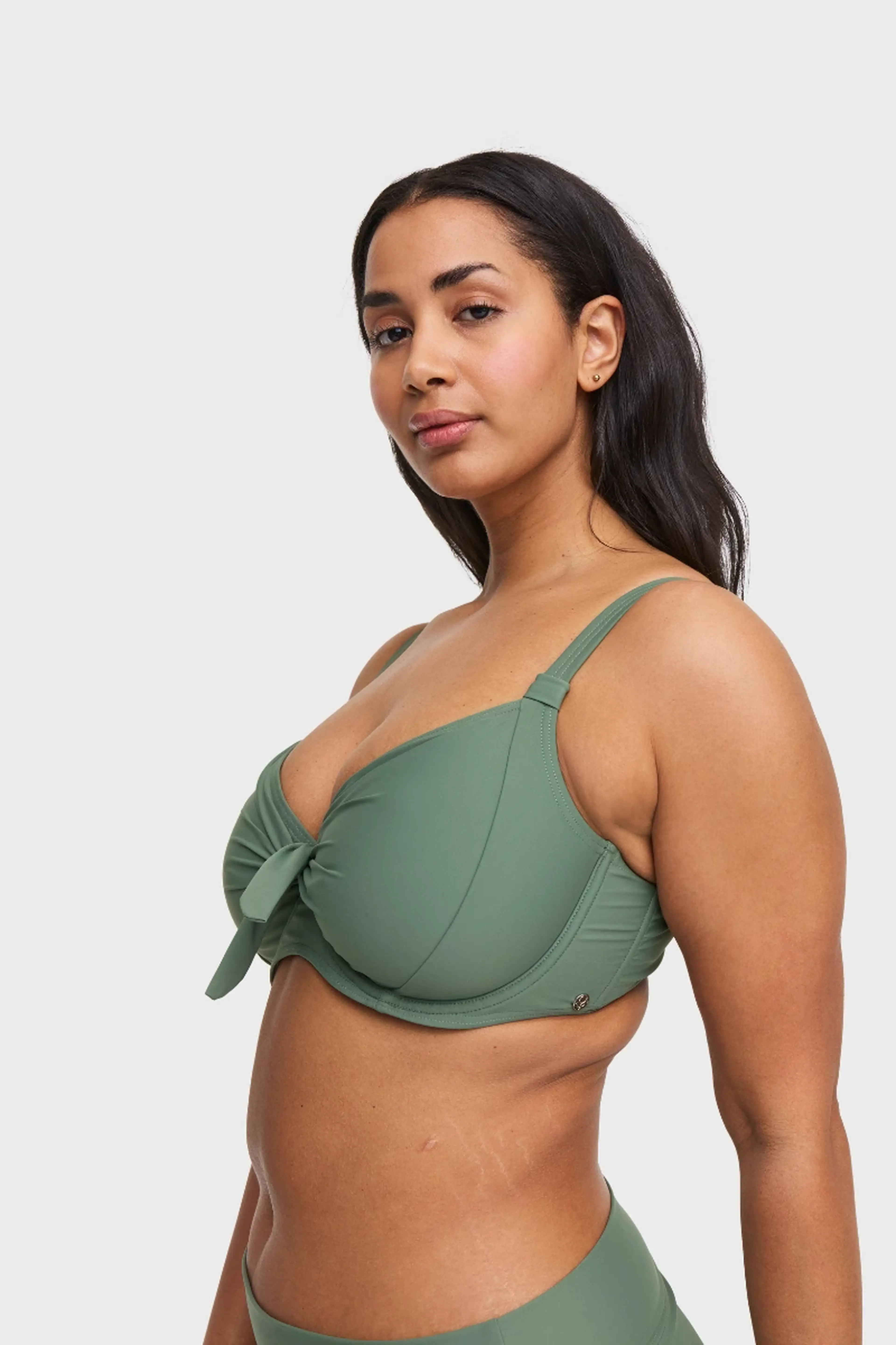 Person wearing a Swegmark green bikini, looking confidently at the camera. The background is plain white.