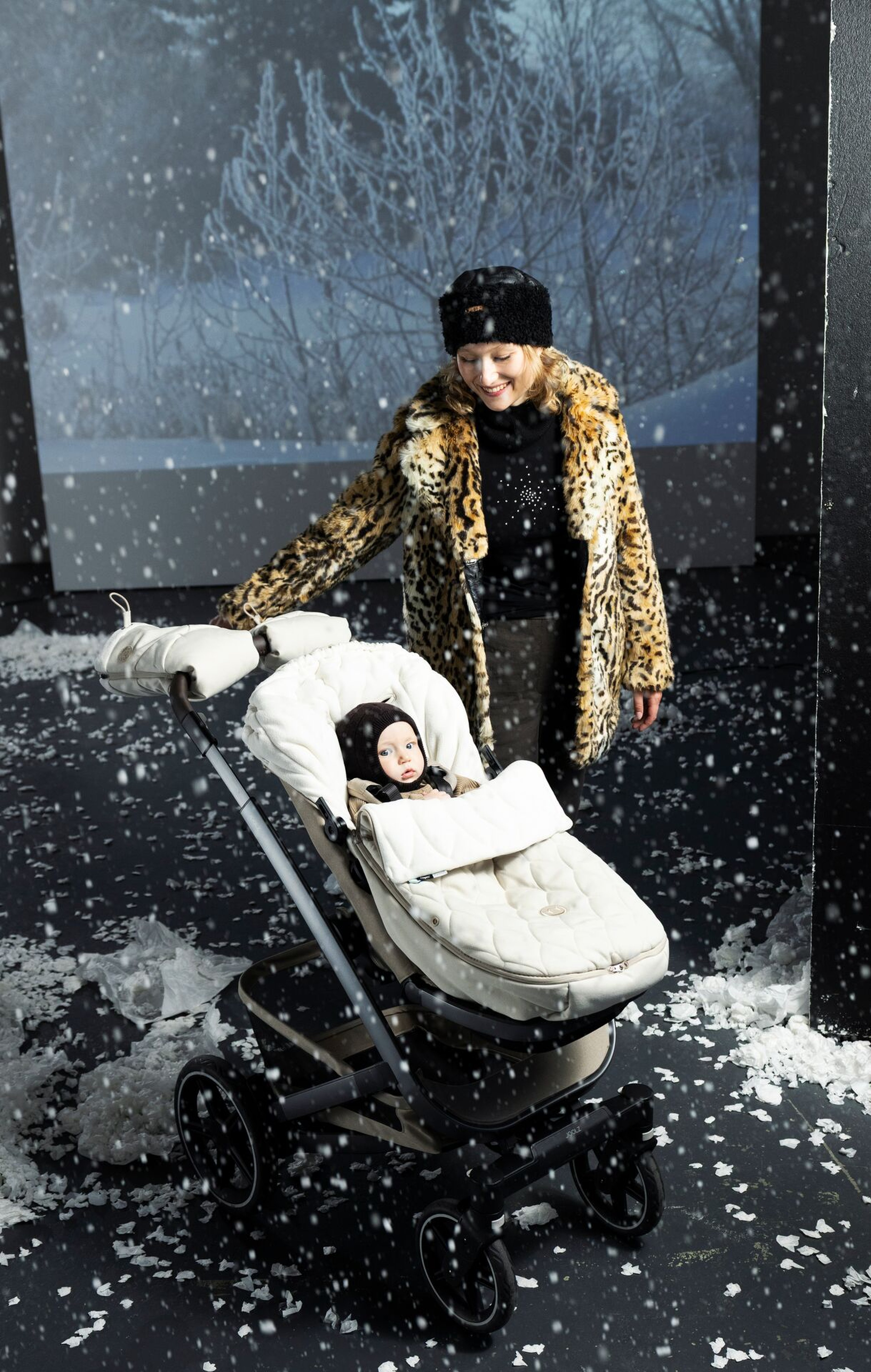 Beige universal footmuff with matching stroller gloves on a stroller in snowy winter weather.