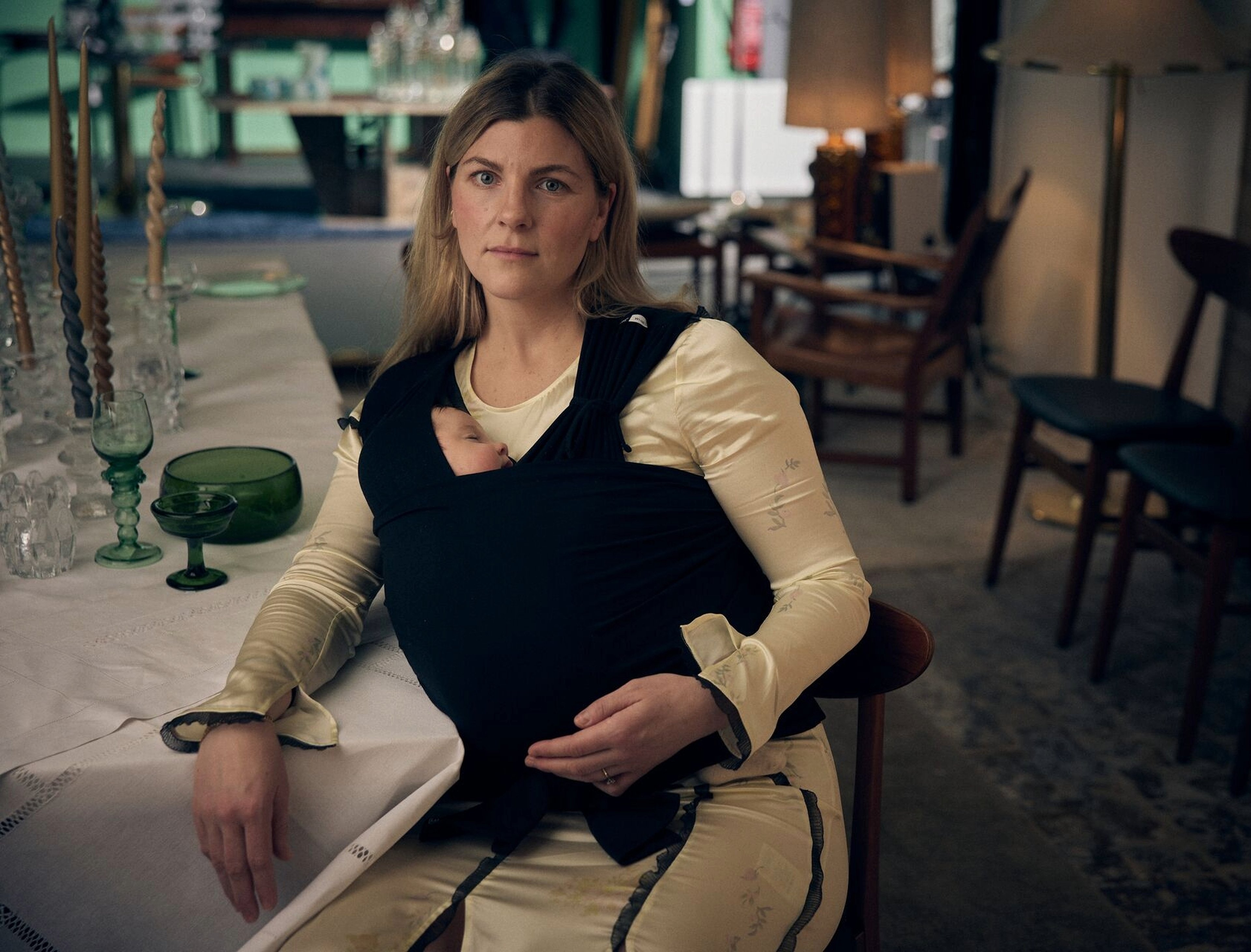 Forelder bærer en nyfødt i Najell Wrap ferdigknyttet bæresjal i en innovervendt bæreposisjon