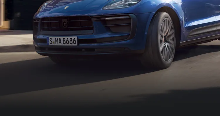 Porsche Macan em Azul Gentian metálico dirigindo pela cidade. Vistas frontal e lateral.