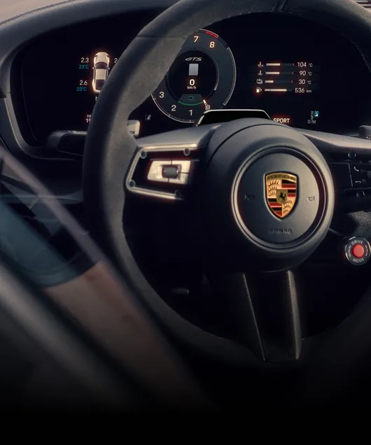 View of the steering wheel and the instrument cluster or curved display in the Porsche 911.
