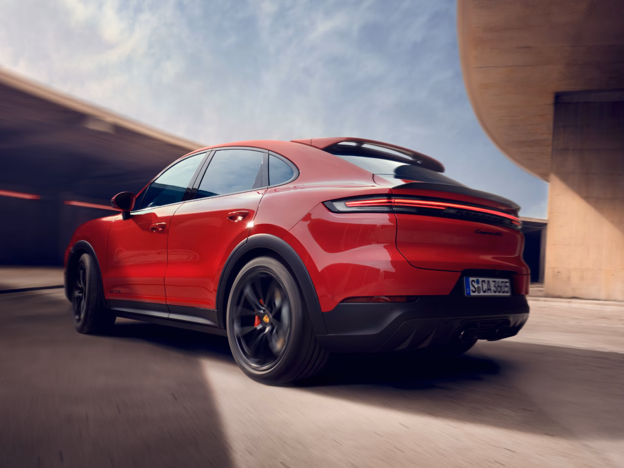 <p>Vista da dietro della parte posteriore e laterale di una Porsche Cayenne GTS Coupé in movimento.</p>