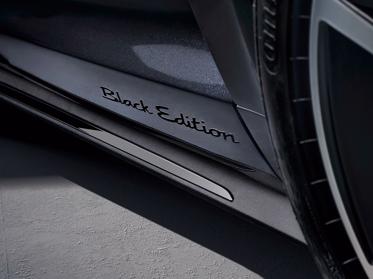 Detailansicht des "Black Edition" Schriftzuges in Schwarz an den vorderen Türen des Porsche Taycan 4S Black Edition mit Erweiterungspaket Black Edition.