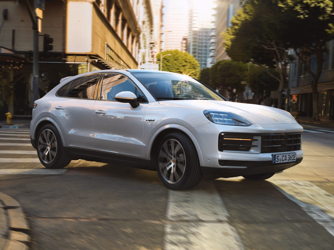 Porsche Cayenne S E-Hybrid Coupé in Carrara White Metallic driving along a highway. Front and side views from the front.