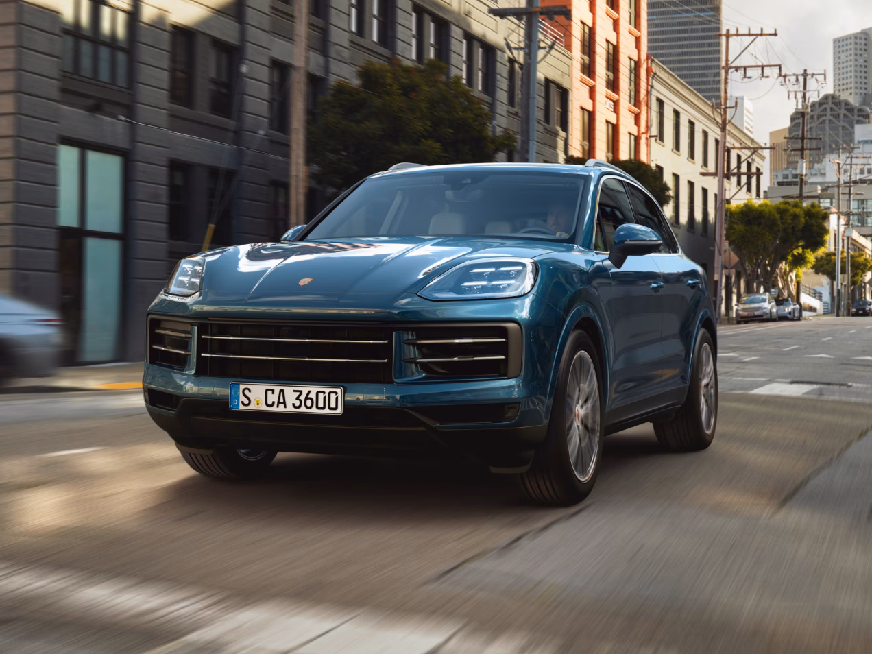 Porsche Cayenne en color Azul Montego Metalizado circula por la ciudad. Vista desde delante de la parte delantera.