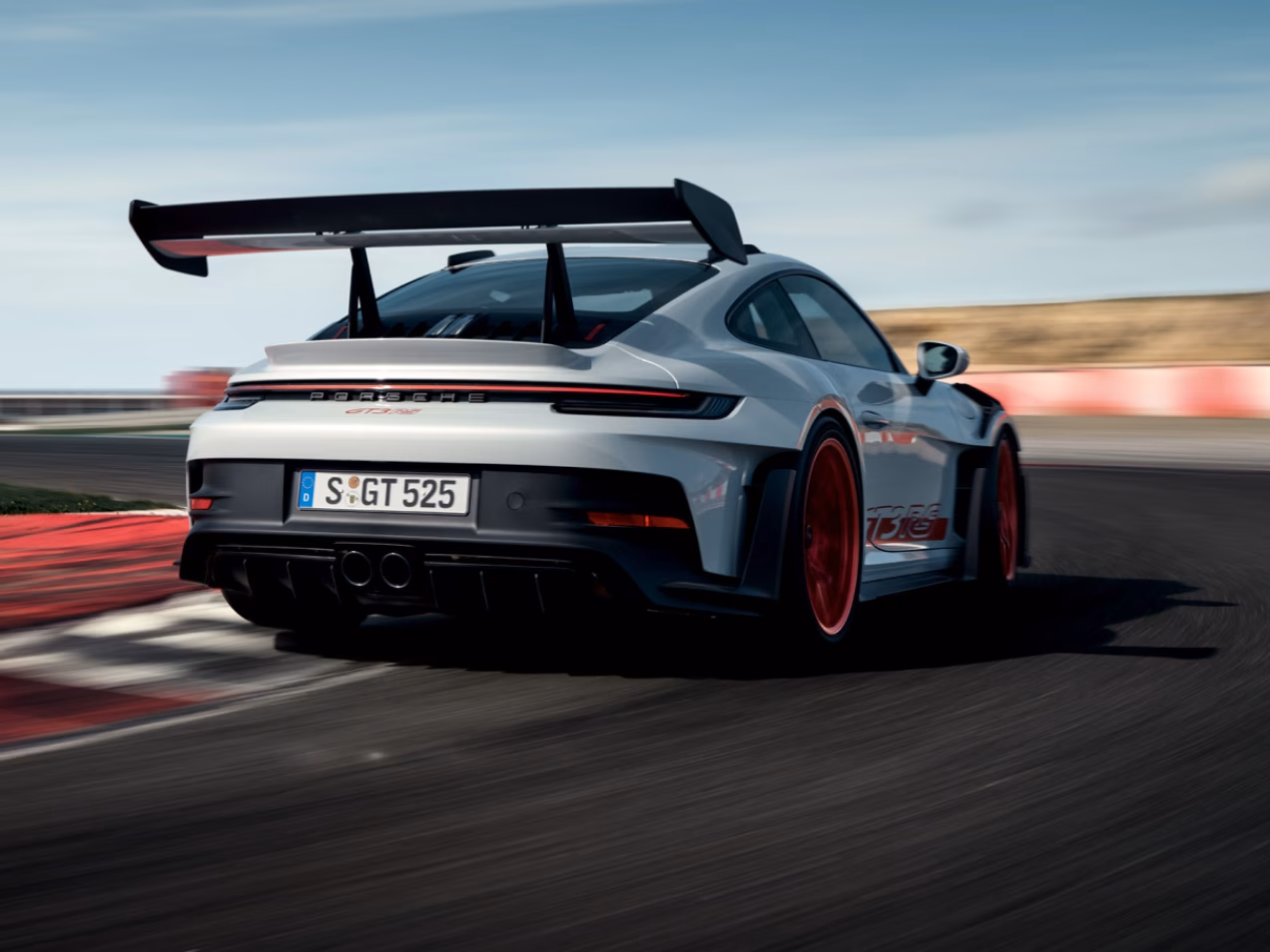 Porsche 911 GT3 RS in Eisgraumetallic fährt auf Rundstrecke um Kurve. Blick von hinten aufs Heck.