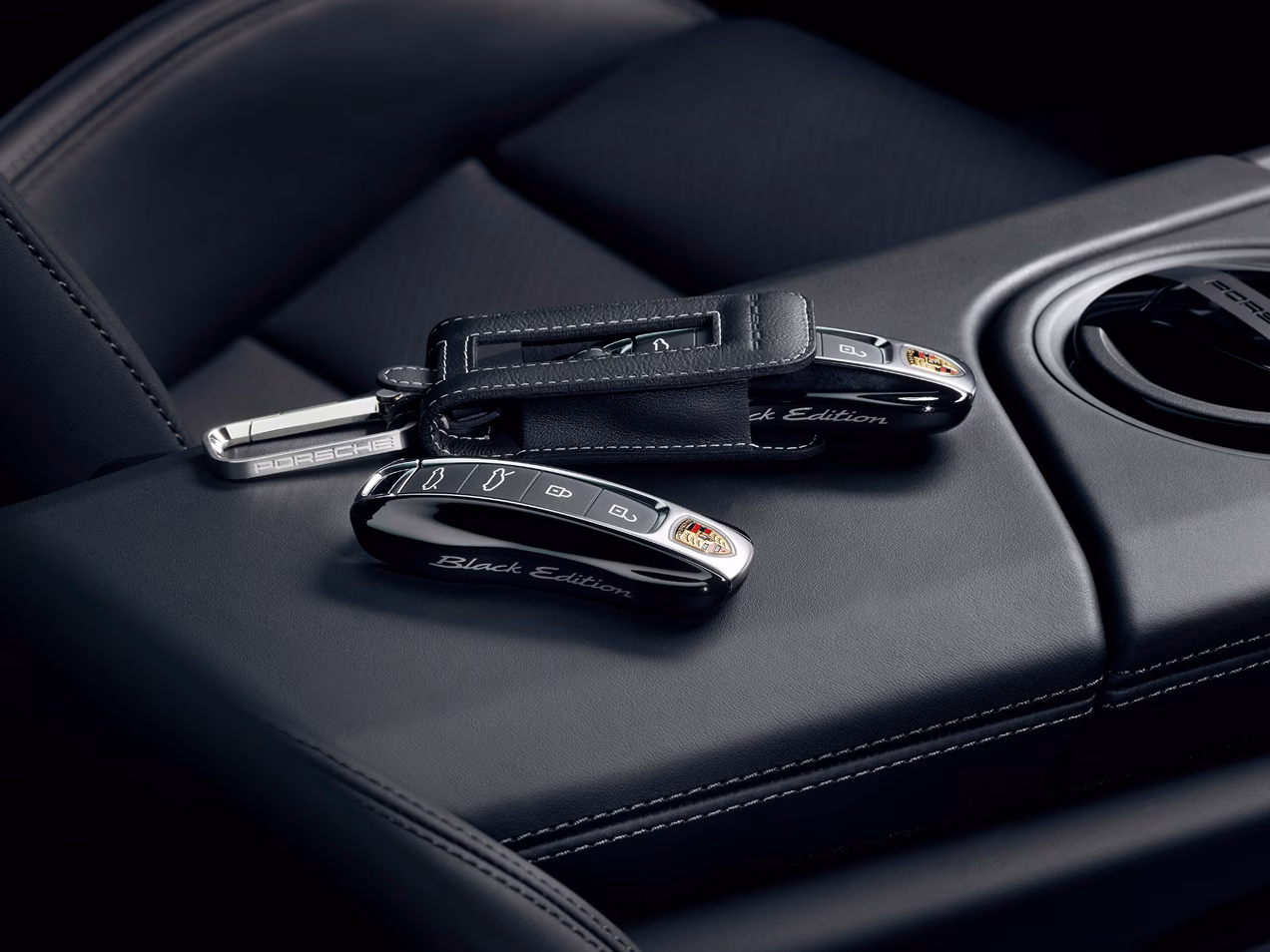 Detailansicht der 2 Fahrzeugschlüssel mit „Black Edition“ Schriftzug und des Schlüsseletuis von dem Porsche Taycan 4S Black Edition mit Erweiterungspaket Black Edition.