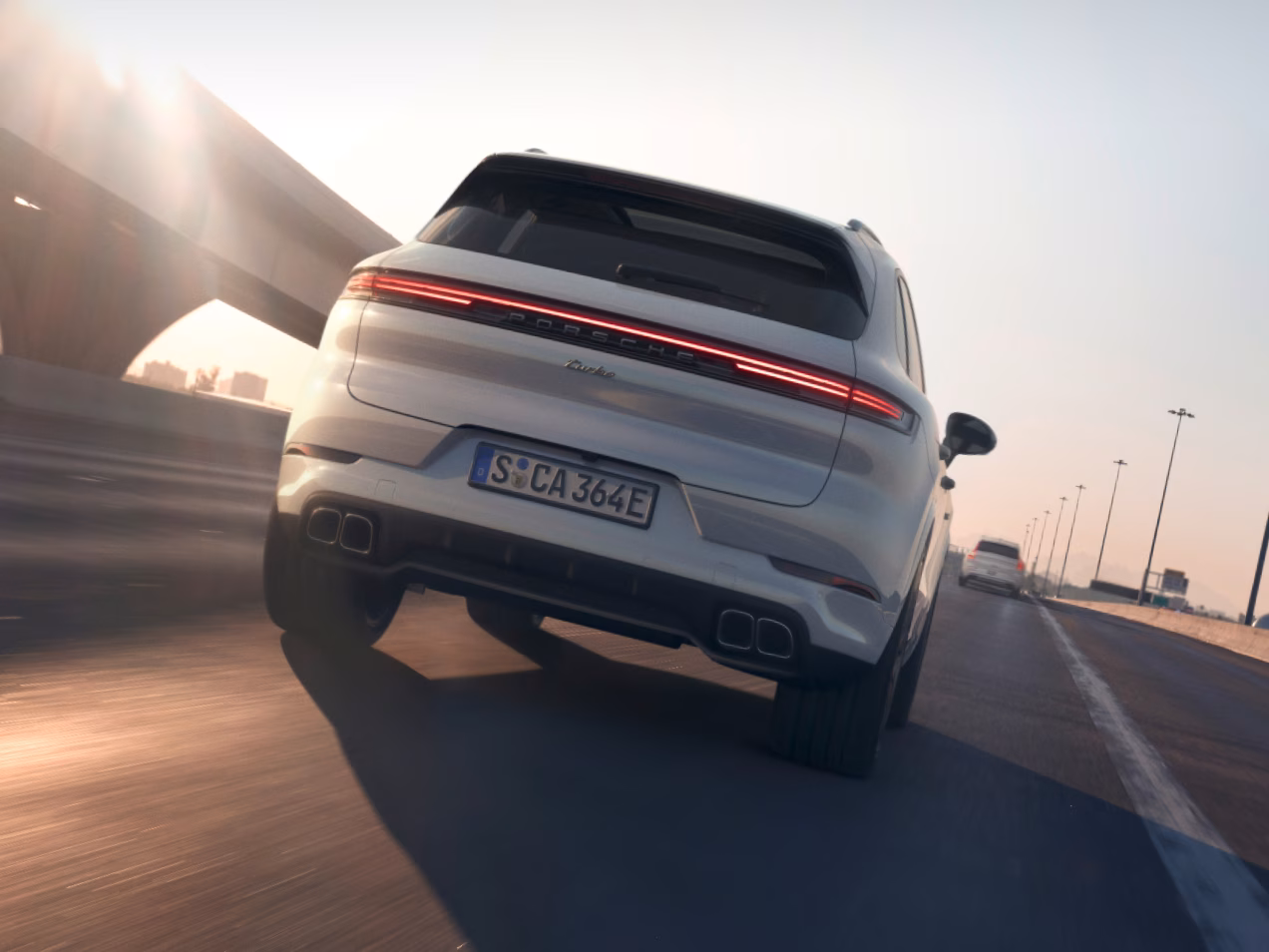 Porsche Cayenne Turbo E-Hybrid in Carrarawit metallic rijdt op de snelweg. Blik van achteren op de achterkant.