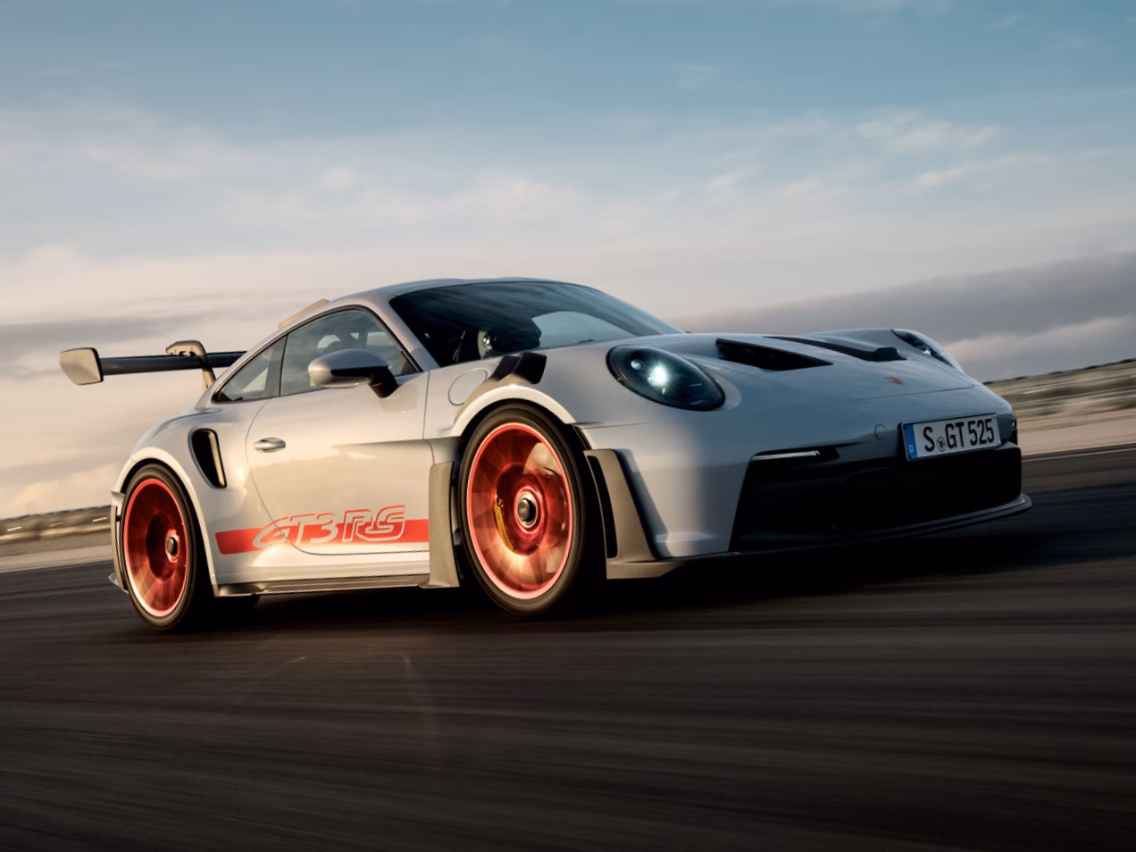 Porsche 911 GT3 RS in ijsgrijs metallic rijdt op het circuit. Zicht op de voorzijde en de zijkant.