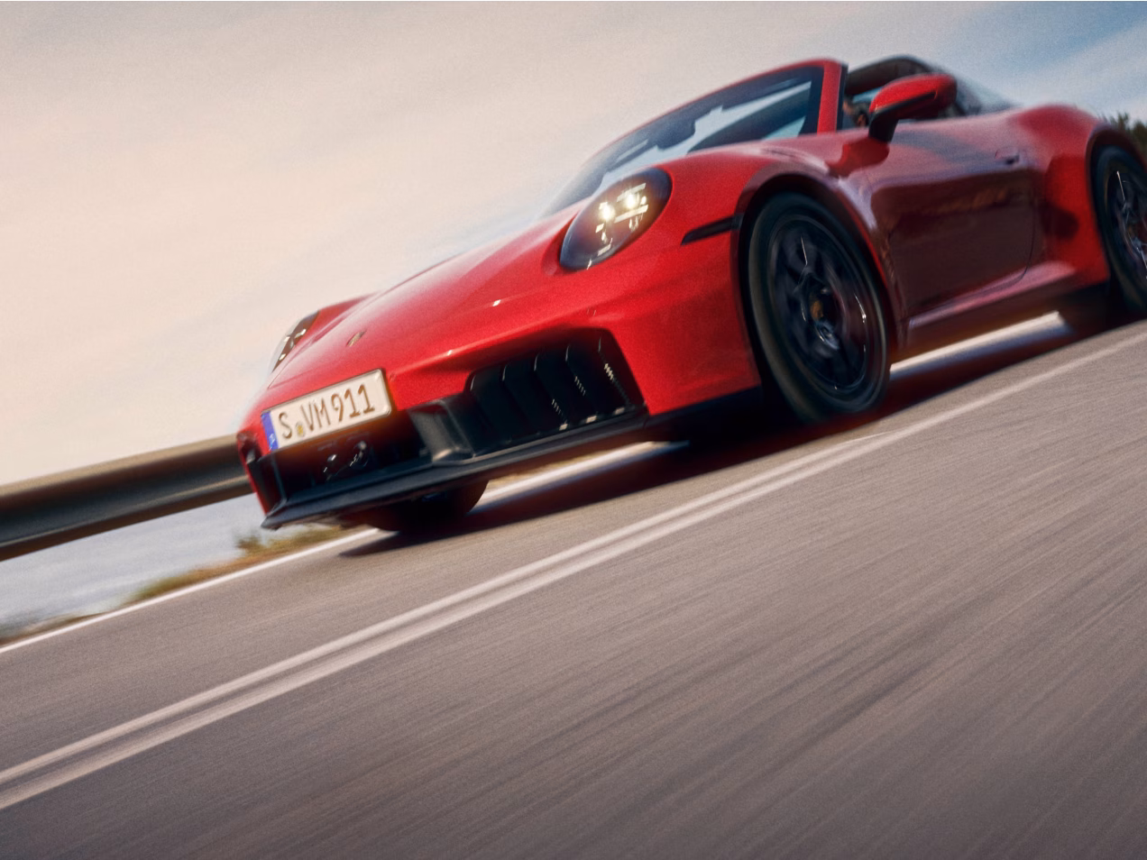 Porsche 911 Targa 4 GTS in Carmine Red driving on a road. Front and side views from the front.