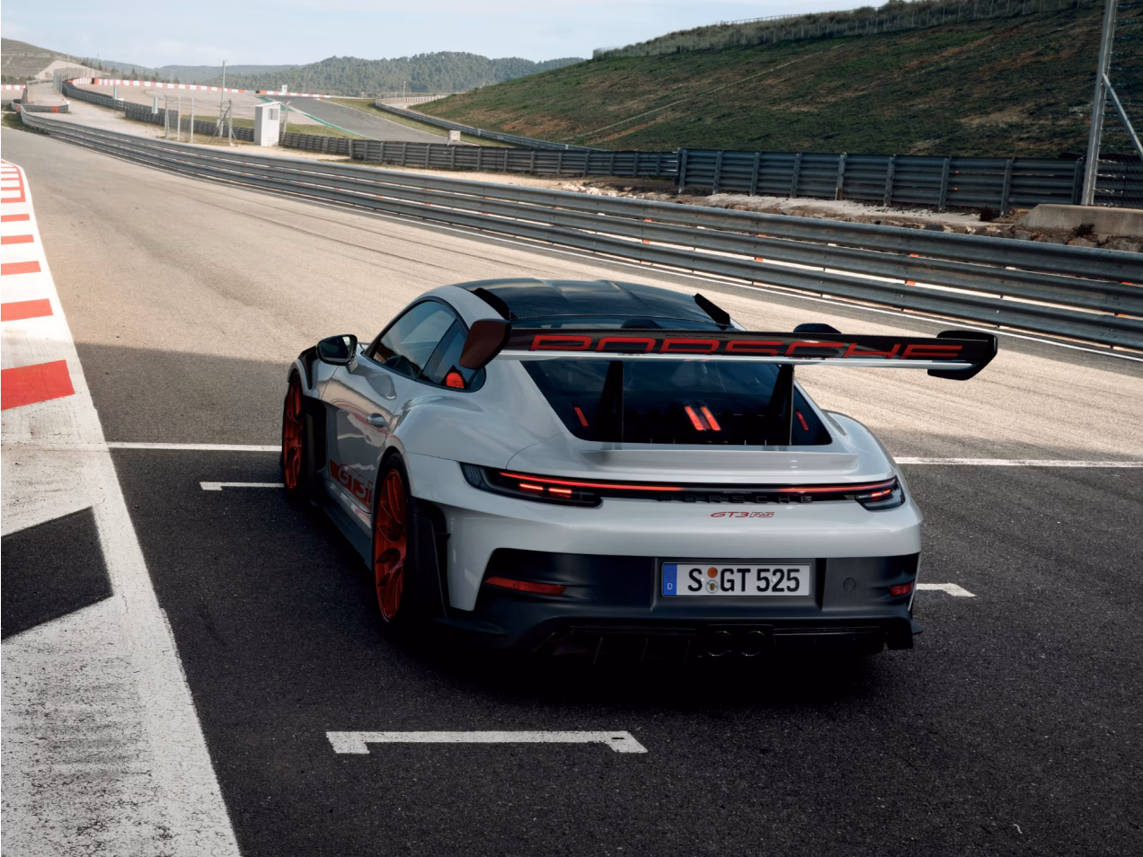 The Porsche 911 GT3 RS in Ice Grey Metallic on the starting line on a race track. View of rear end from behind.