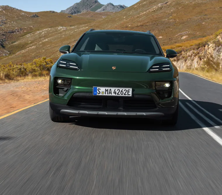 Porsche Macan 4S in Oakgrünmetallic fährt durchs Gelände. Seite und Front sichtbar.