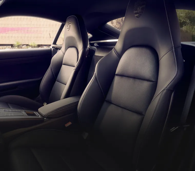 Салон Porsche 718 Cayman Style Edition: детальное изображение спортивных сидений с тисненым гербом Porsche на подголовниках.
