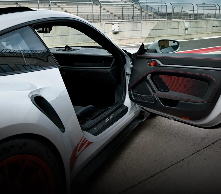 The Porsche 911 GT3 RS in Ice Grey Metallic on a race track. View of the open passenger's door.